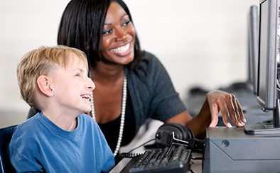 Teacher and student looking at computer screen together and smiling